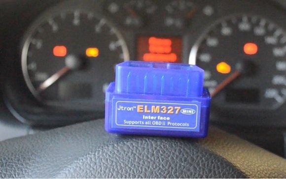Conector ELM 327 sobre o volante de um carro
